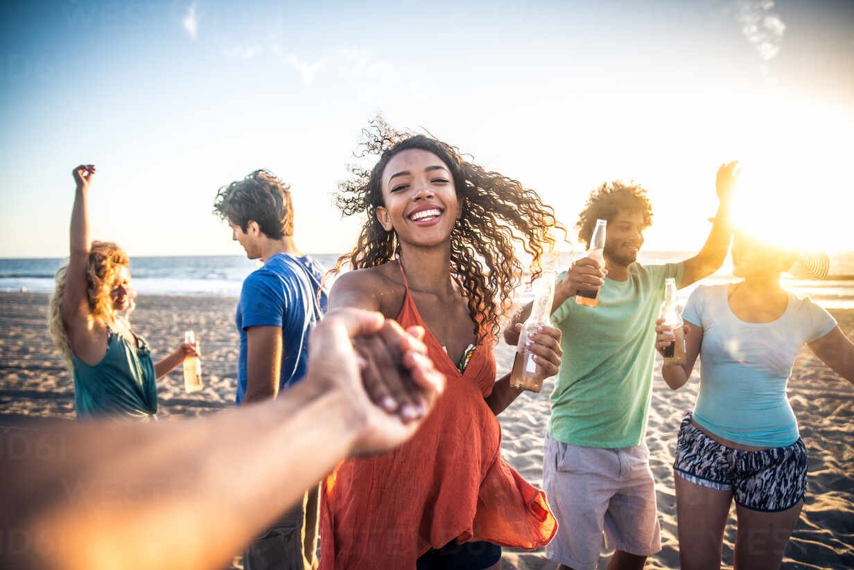 Multicultural group of friends partying on the beach - Young people celebrating during summer vacation, summertime and holidays concepts